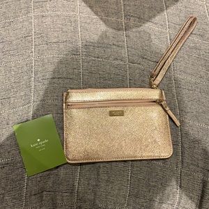 Kate Spade New York shiny champagne wristlet with gold hardware and care card.